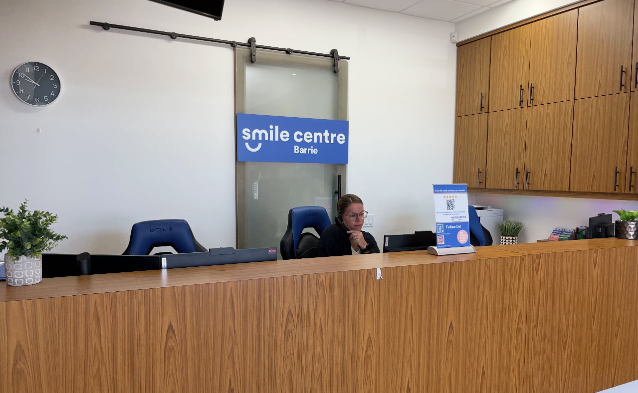 Reception area at Barrie Smile Centre dental clinic in Barrie, ON with front desk, staff member, and modern office interior.