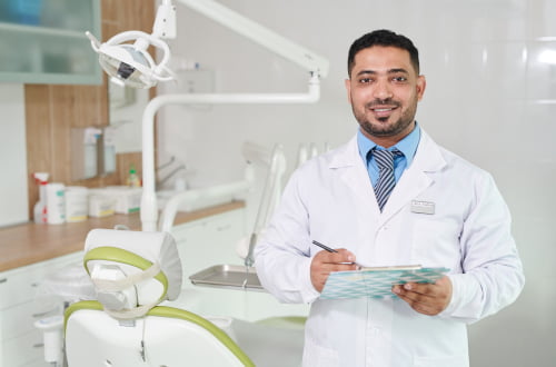 A dentist holding a clipboard during a consultation about the Canadian Dental Care Plan