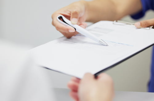 Patient discussing documents with a dental clinic staff member during a CDCP appointment