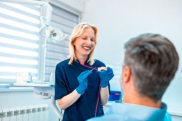Dentist showing a dental bridge model during a consultation with a patient.