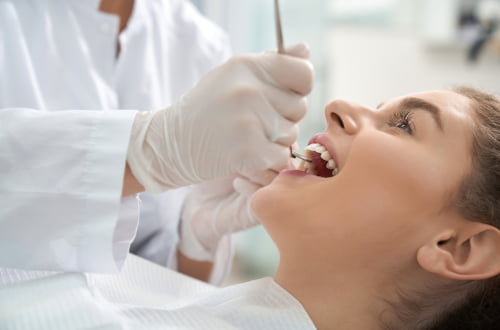 Patient receiving emergency dental treatment while lying in a dental chair during an urgent exam