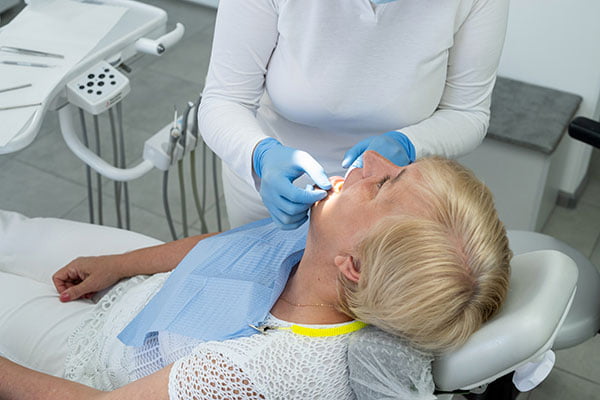 Female dentist discussing the right time for wisdom teeth removal with a senior patient during a dental exam