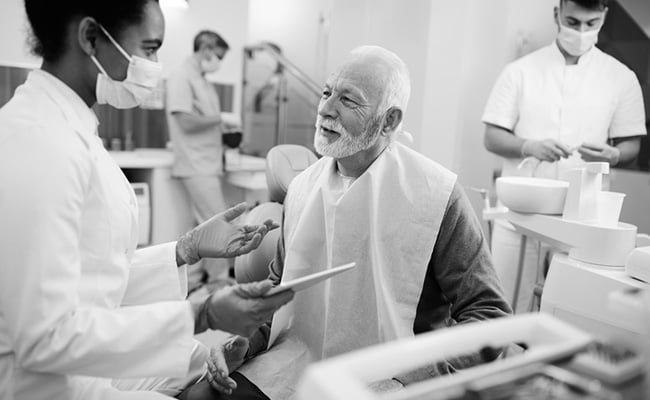 Senior patient discussing alternatives to dentures with a dentist during a dental consultation.