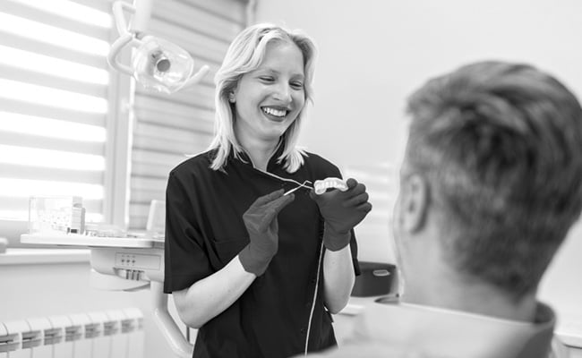 Dentist showing a dental bridge model to a patient during a restorative dentistry consultation in Barrie