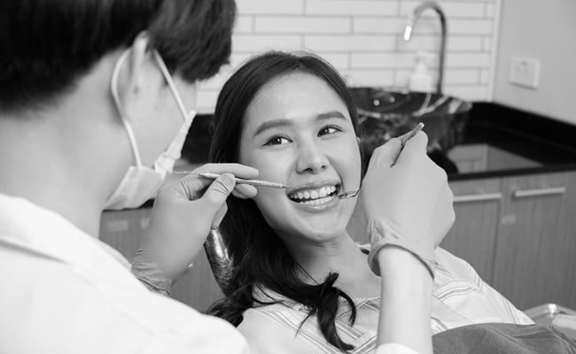 Dentist performing a routine dental check-up for a female patient in a modern dental clinic