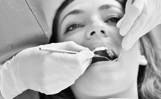 Female patient receiving a dental examination before dental crown treatment at a dental clinic.