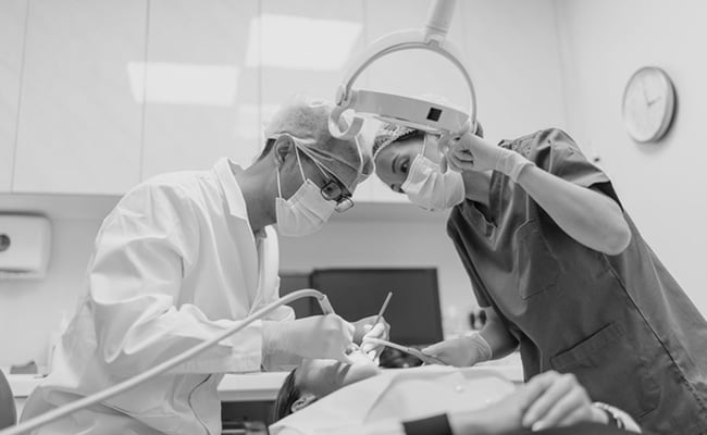 Dentist and dental assistant performing a dental surgery procedure in a modern dental clinic.