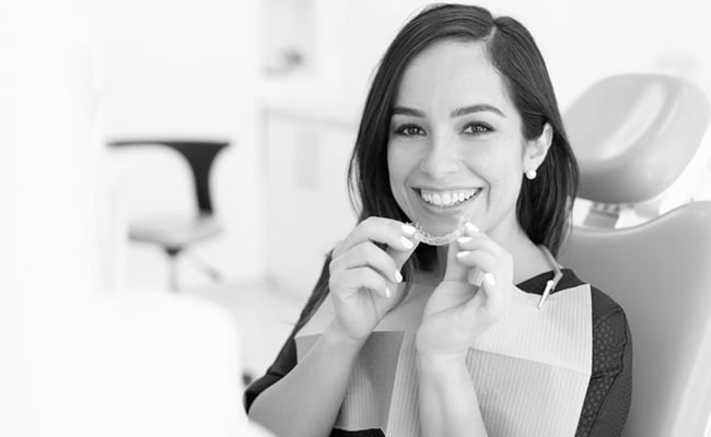 Patient holding clear Invisalign aligners during an orthodontic consultation at a dental clinic in Barrie