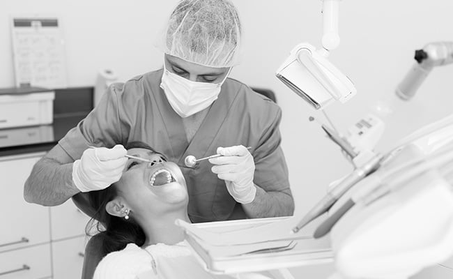 Dentist examining a patient’s teeth before treatment with white mercury-free fillings.