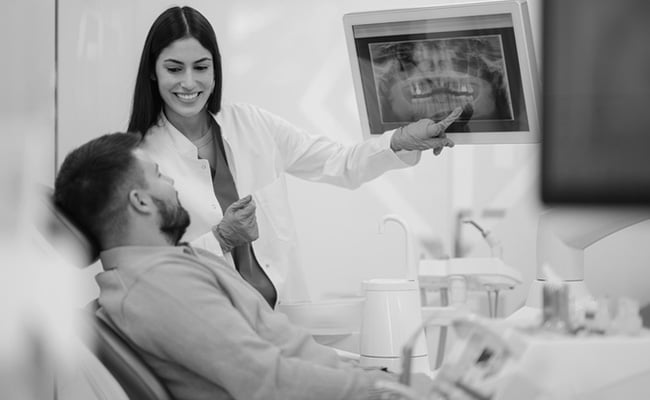 Dentist reviewing a dental X-ray with a patient during a wisdom teeth removal consultation in Barrie