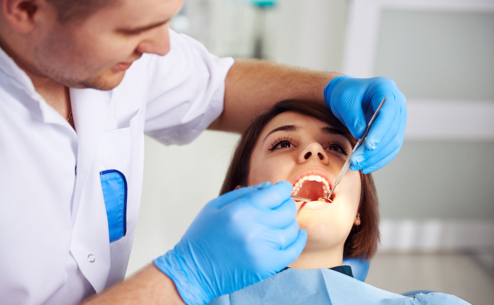 Dentist examining patient with a lost dental filling or dental crown emergency