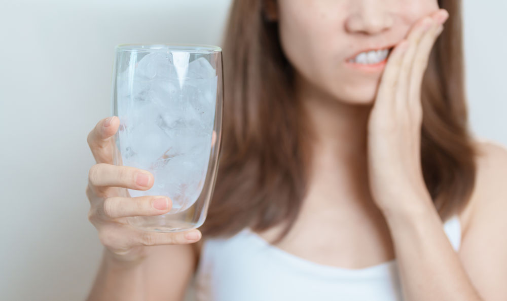 Woman experiencing tooth sensitivity to cold, a possible cracked tooth symptom